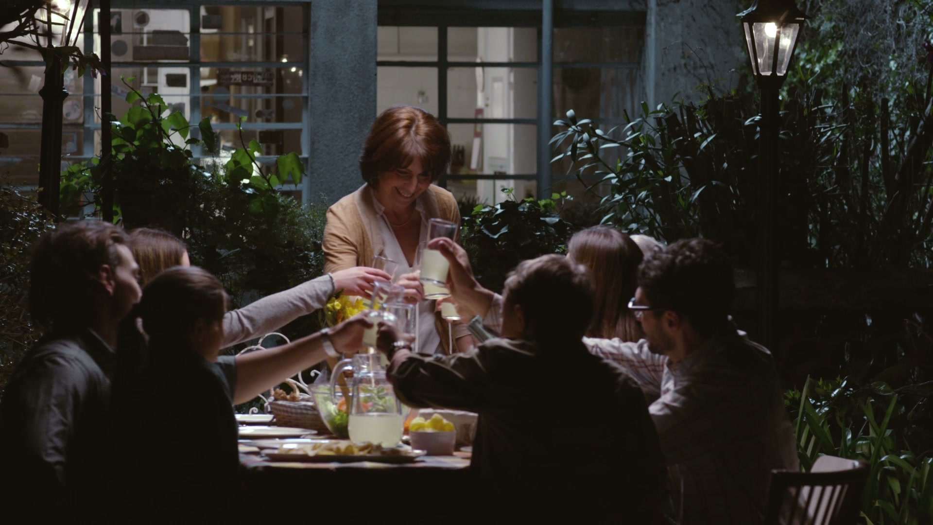 Una familia brinda alrededor de la mesa en un patio, escena del spot de los 100 años de Molino Puritas