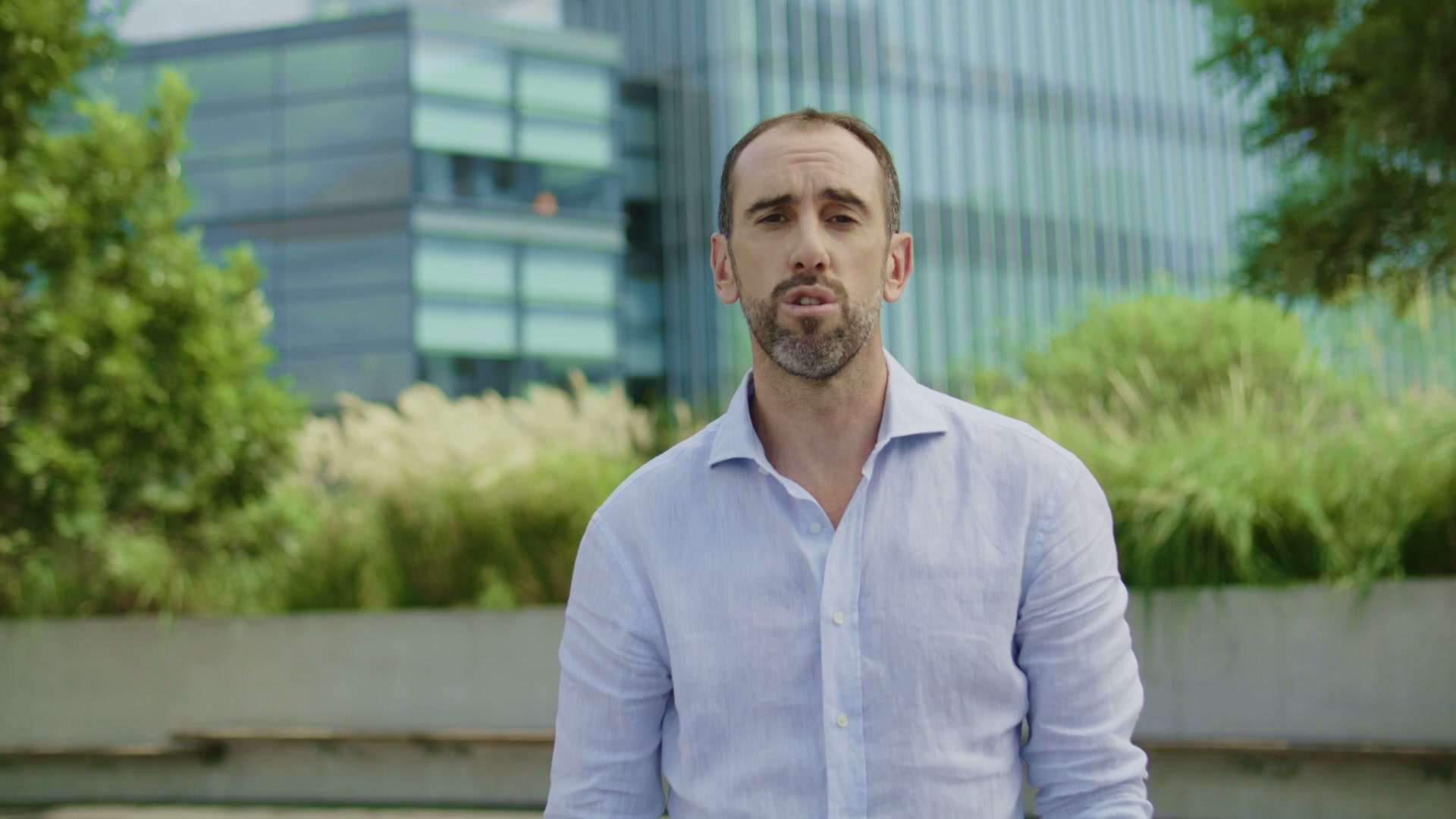 Diego Godín de frente, con camisa celeste, en una calle con edificios de fondo